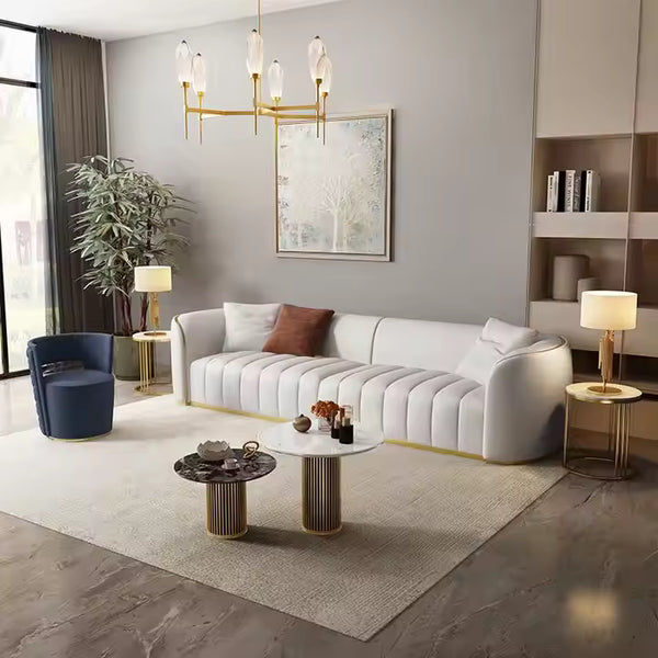 Sofá moderno blanco con capitoné y detalles dorados.