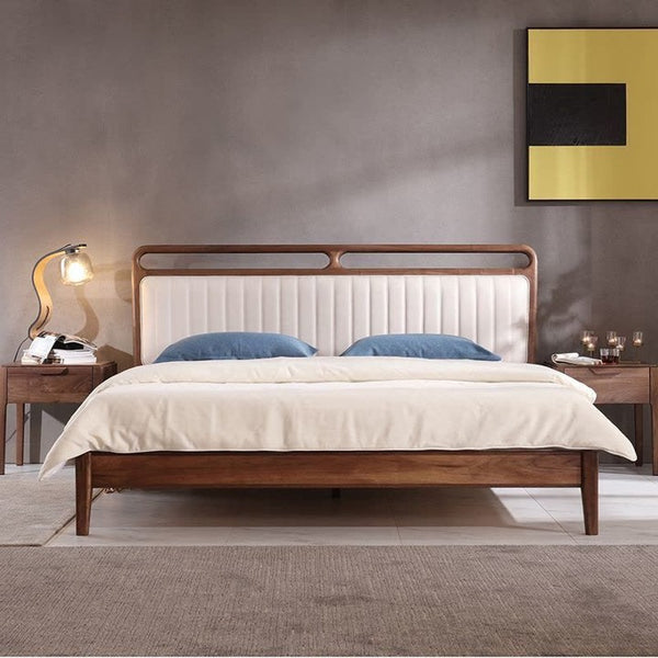 Cama moderna de mediados de siglo: estructura de madera esculpida y cabecera tapizada con canales verticales.