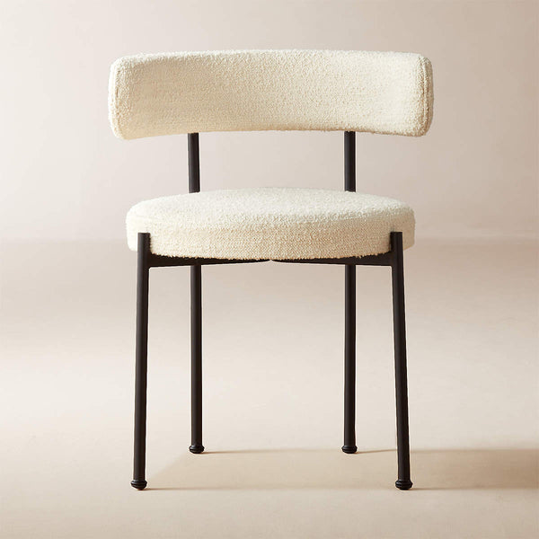 Silla de comedor moderna tapizada en bouclé: estructura de metal negro y respaldo curvo.