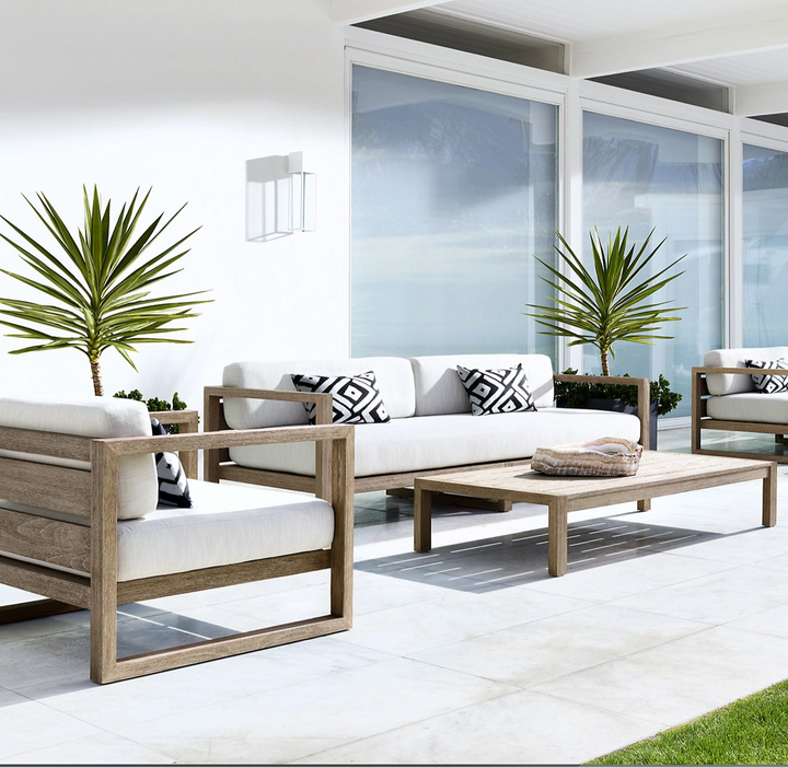Outdoor patio furniture set with white cushions and wooden frames on a modern patio.