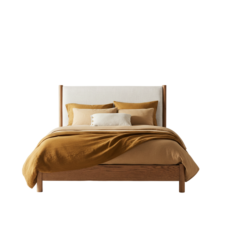Wooden bed with mustard yellow bedding and pillows against a white background