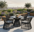Outdoor patio set with black metal chairs and table on a rooftop with cityscape view.