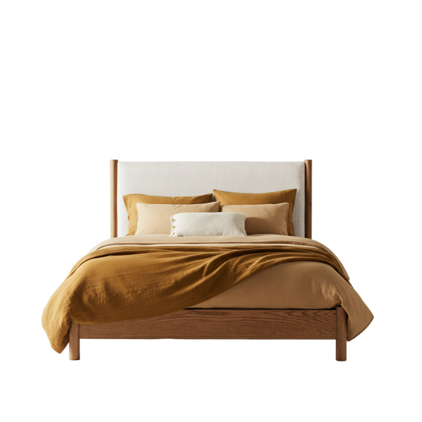 Wooden bed with mustard yellow bedding and pillows against a white background