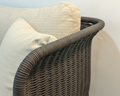 Wicker chair with beige cushions against a light background